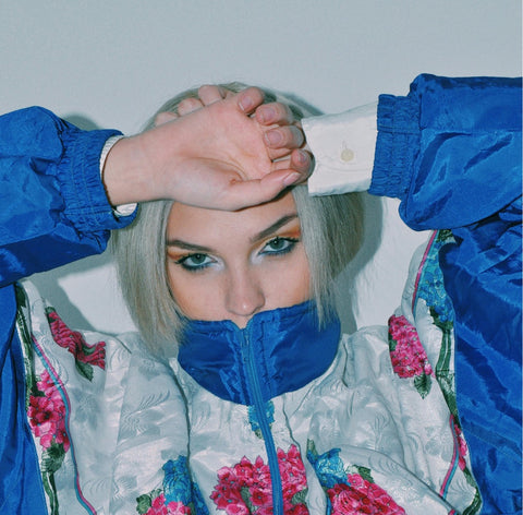 Blonde Frau mit Retrojacke & Blumenmuster – auffälliger Stil passend zu ENNY-Brille.