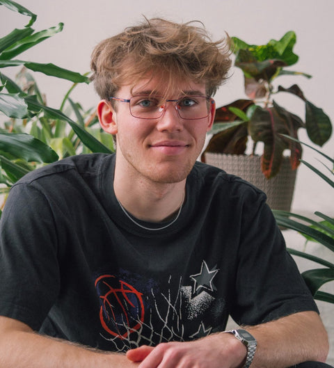 Model trägt eckige dunkelblaue Herrenbrille mit orangen Details im sportlichen Look