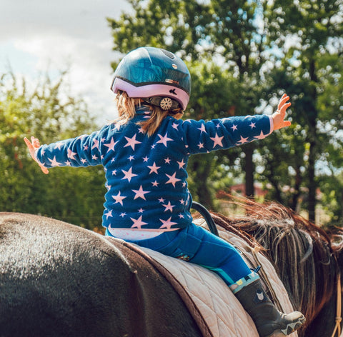 Kind auf Pferd mit ausgestreckten Armen – Freiheit & Individualität mit ENNY-Brillen.