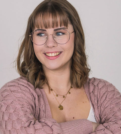 Model trägt rot-goldene Schmetterlings-Damenbrille mit Zierrand und lächelt