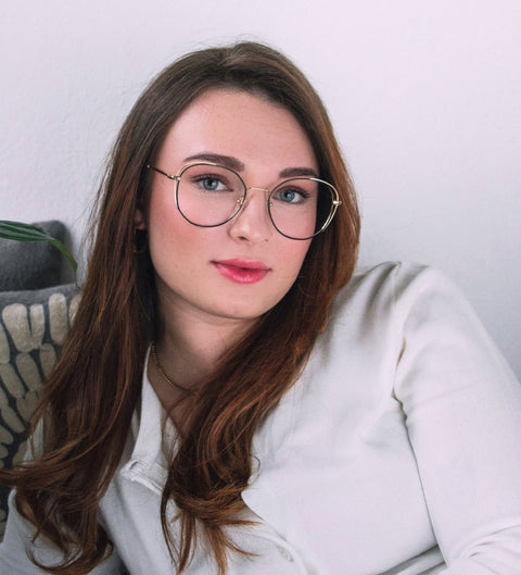 Model trägt schwarze Schmetterlings-Damenbrille mit goldenen Akzenten im Alltag auf dem Sofa