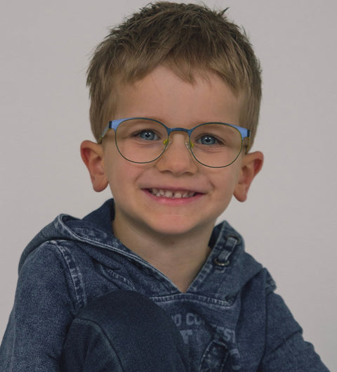 Kind mit runder blau-gelber Kinderbrille aus Metall von ENNY – stilvoller Look im Alltag.