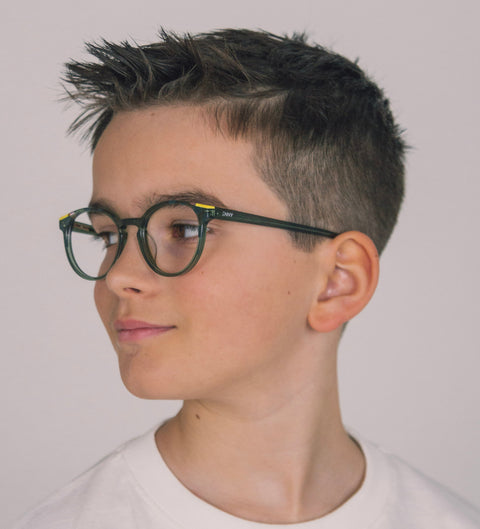 Junge mit kurzem dunklem Haar trägt die Kinderbrille Turi in halbtransparentem Olivgrün und schaut selbstbewusst zur Seite