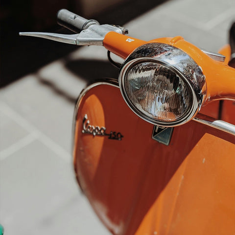 Leuchtend orangene Vespa im Retro-Stil – der perfekte Hingucker für Vintage-Fans.